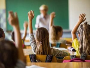 Crianças com as mãos levantadas em uma sala de aula