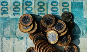 Dinheiro em espécie, com notas de R$ 100 e moedas de real, em imagem ilustrativa.