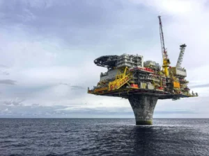 lataforma petrolífera offshore sobre uma coluna central de concreto no meio do oceano, sob um céu nublado.